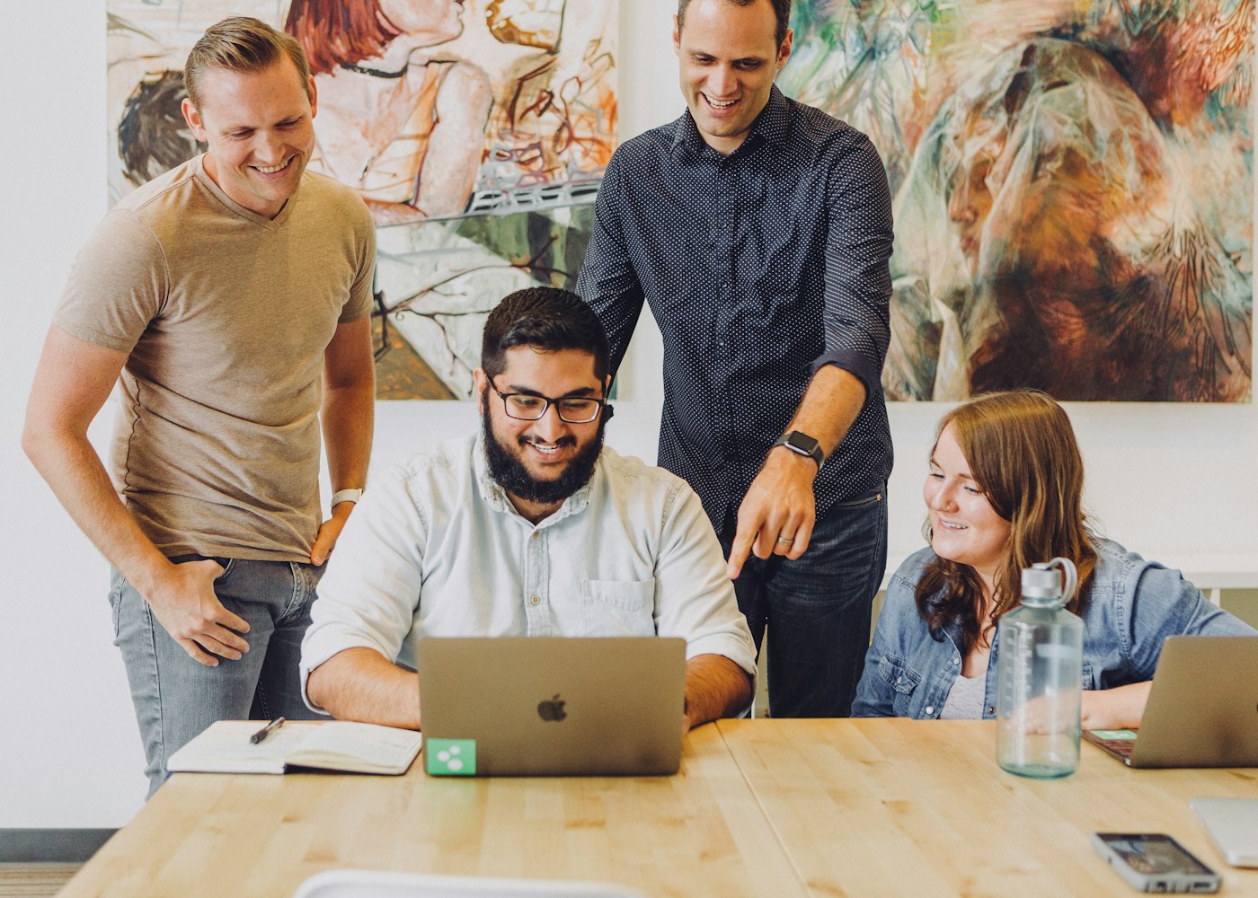 Four colleagues gathered around a laptop